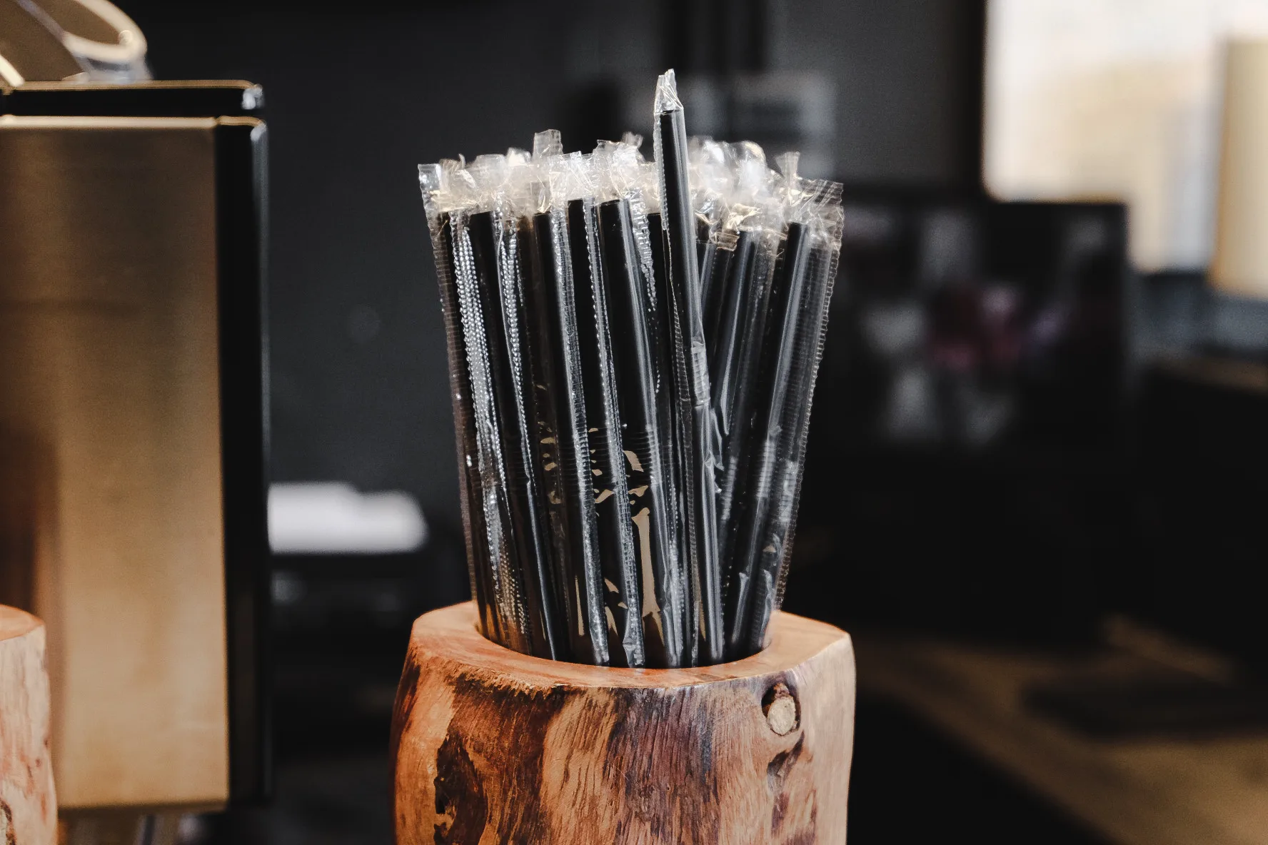 หลอดพลาสติกห่อซองบนเคาน์เตอร์คาเฟ่ · wrapped drinking straws in a café counter holder